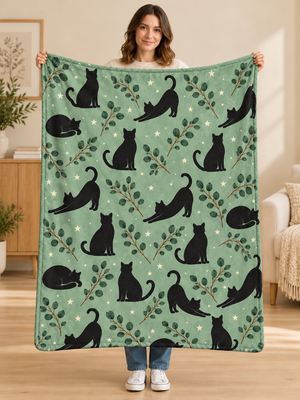 Woman holding a sage green fleece blanket with black cat silhouettes