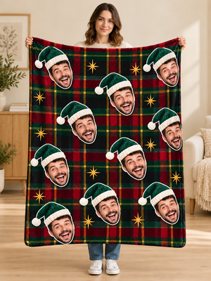 Woman holding a red and green plaid fleece blanket with a repeating face in a Santa hat